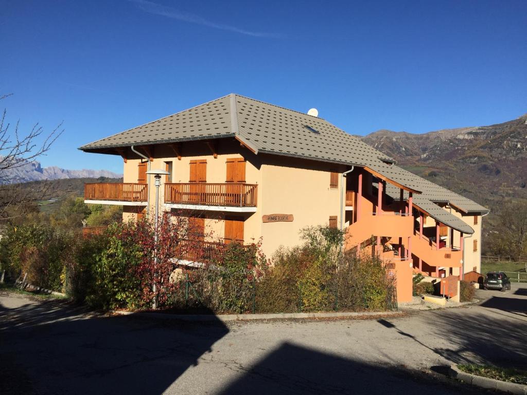 Une grande maison avec balcon est située dans une rue. dans l'établissement Appartement offrant une magnifique vue des montagnes, à Saint-Léger-les-Mélèzes