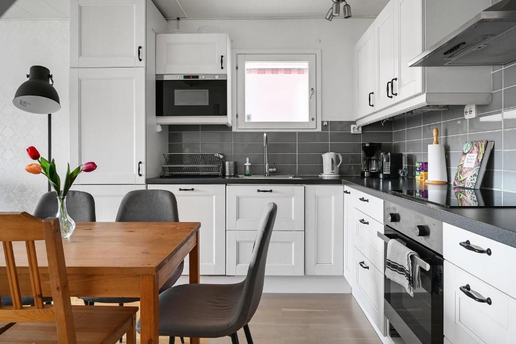 Sparkling modern house in Kista - close to city في ستوكهولم: مطبخ بدولاب بيضاء وطاولة خشبية