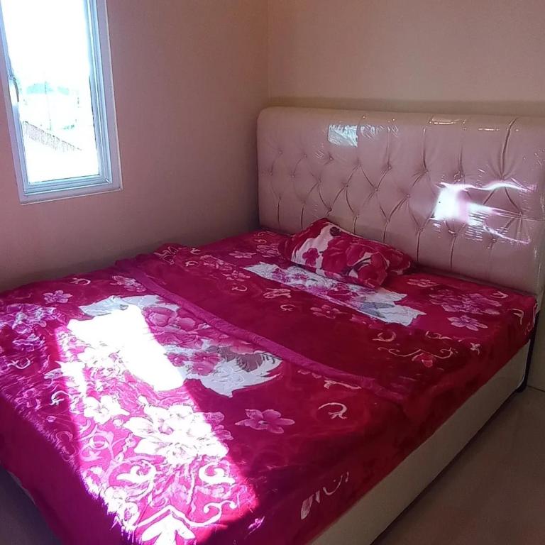 a bed with a pink blanket on top of it at Villa atas awan in Wonosobo