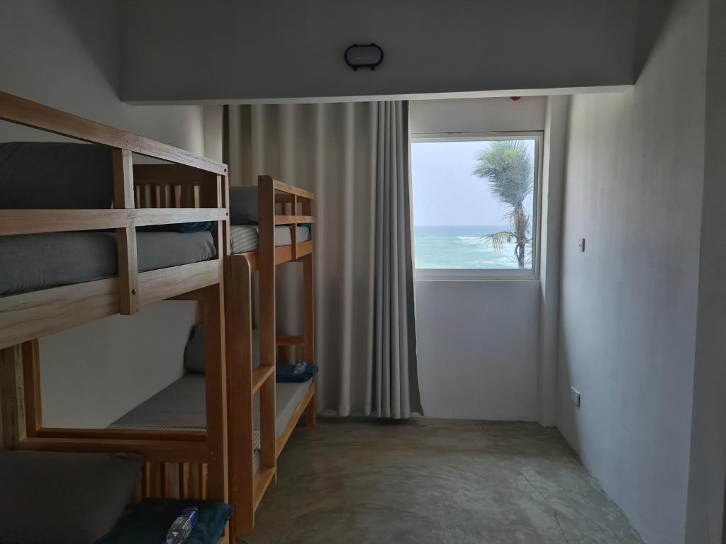- une chambre avec des lits superposés et une fenêtre donnant sur l'océan dans l'établissement Dip N Doze, à Ahangama