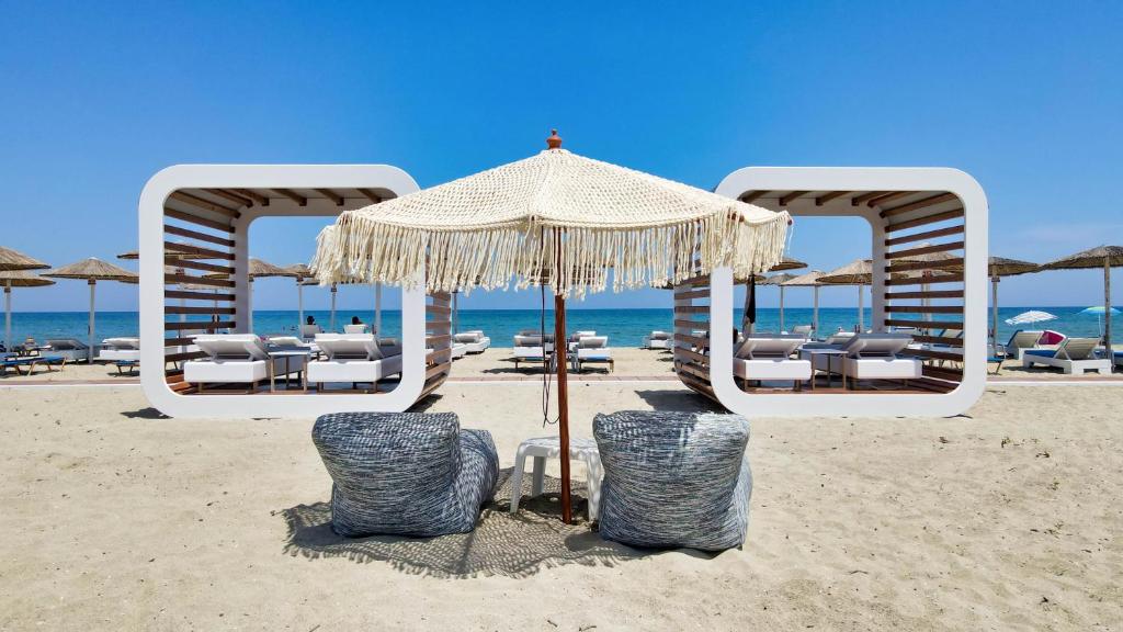 uma praia com cadeiras e um guarda-sol na areia em Hotel Evilion Sea And Sun em Neoi Poroi