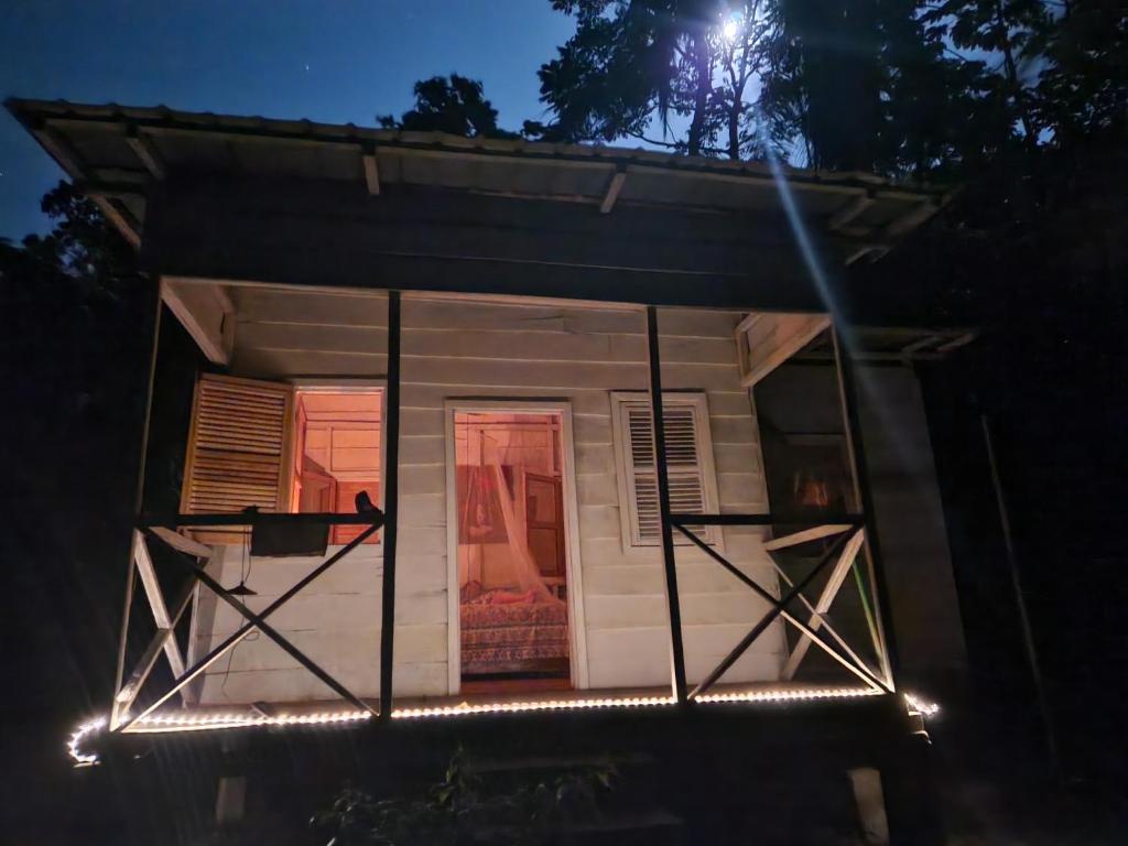 a small house with lights on the front at night at World's View Wild Camping Salaszoi, Principe Island in Santo António