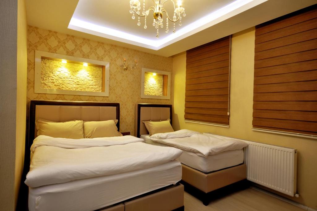 Habitación con 2 camas individuales y lámpara de araña. en Kars Konak Hotel, en Kars