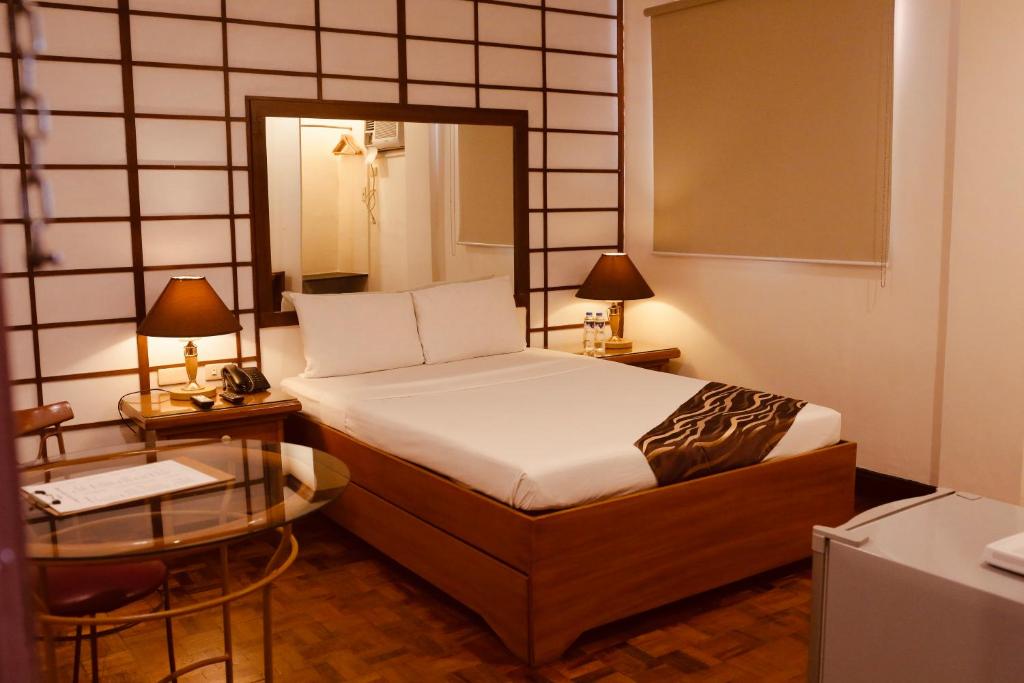 um quarto com uma cama e duas mesas e um espelho em AMALFI718 HOTEL em Lipa