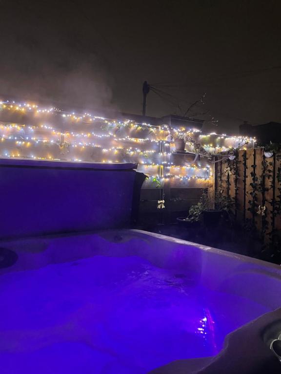 uma banheira de hidromassagem com luzes sobre uma cerca à noite em Honeysuckle Cottage & Whinfell Studio em Penrith