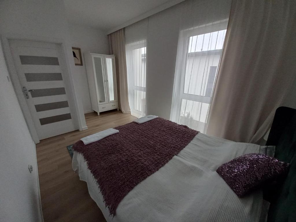 a bedroom with a large bed and two windows at Apartament IGA in Biała Podlaska