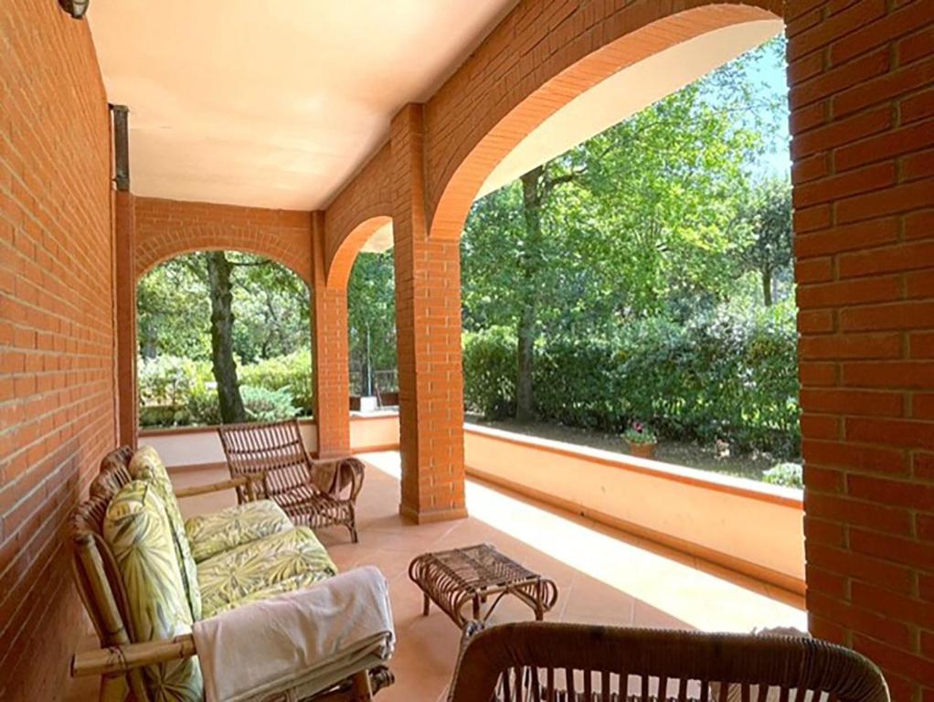 un porche cubierto con 2 sillas y un sofá en Villa DilettaMaria, en Forte dei Marmi