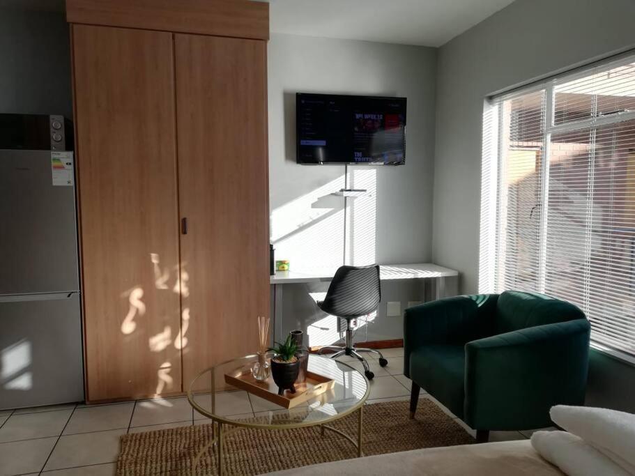 a living room with a glass table and a chair at Cosy apartment with secure parking in Johannesburg