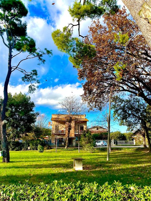 a building in a park with a bench in the grass at MONOLOCALI B&B Santa Maria Apparente in Civitanova Marche