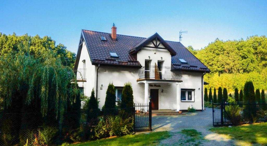 a white house with a black roof at Villa Natalia in Rusinowo