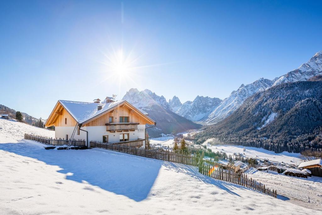 a house in the snow with mountains in the background at Reidenhof in Sesto