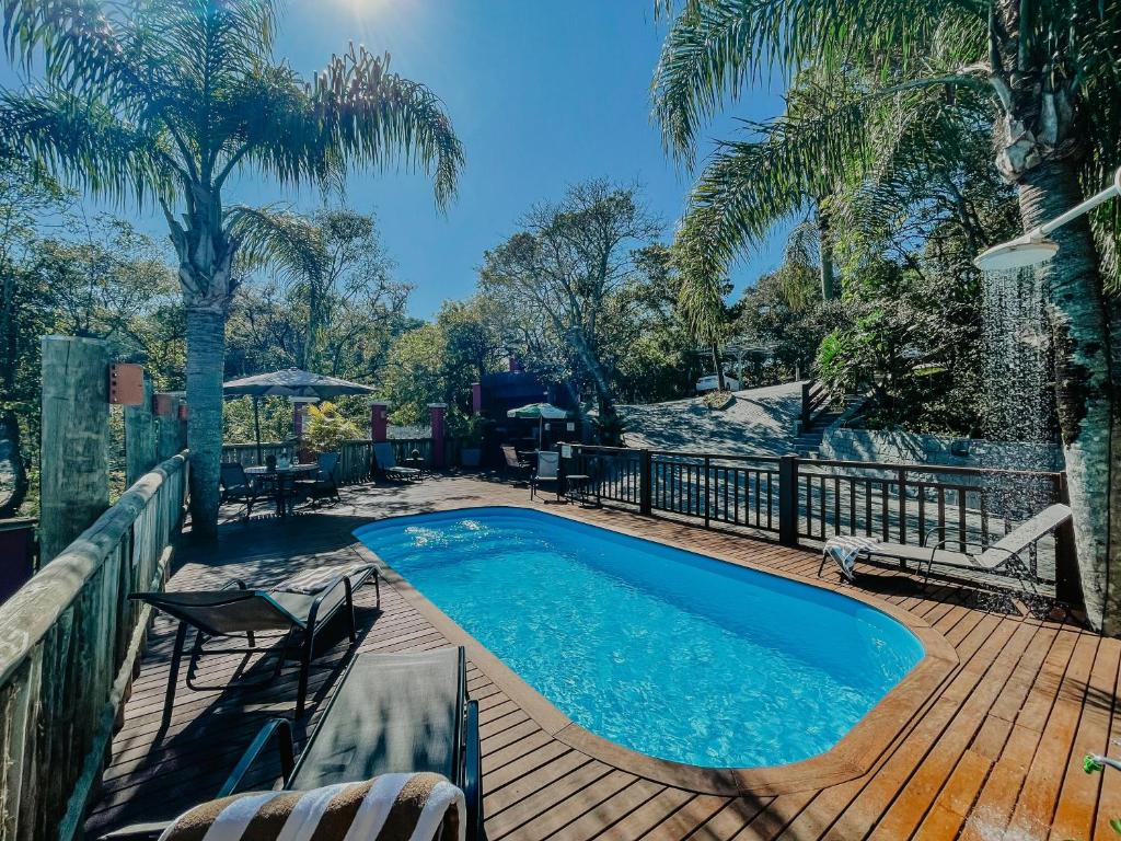 a swimming pool on a wooden deck with palm trees at Dubai Bungalows Bombinhas in Bombinhas