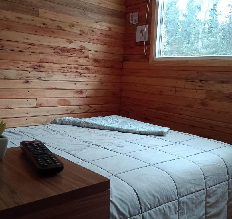 1 dormitorio con cama y mando a distancia en una mesa en Cabaña 2 en Mar del Plata