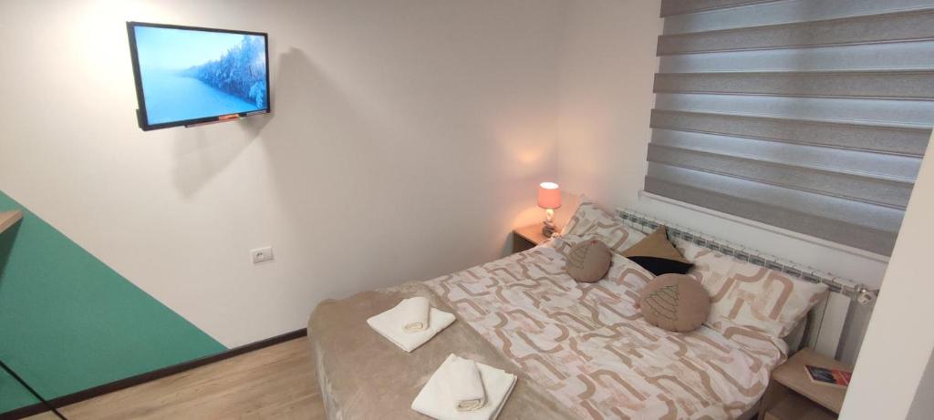a small bedroom with a bed and a tv on a wall at KovacInalux Apartmani in Pale
