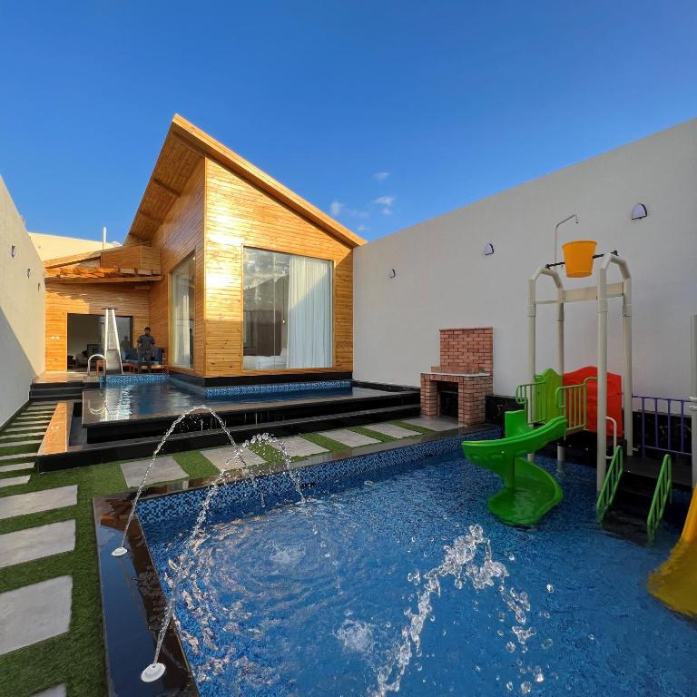 a backyard with a pool with a playground and a house at اكواخ سنتارا الريفيه in Taif