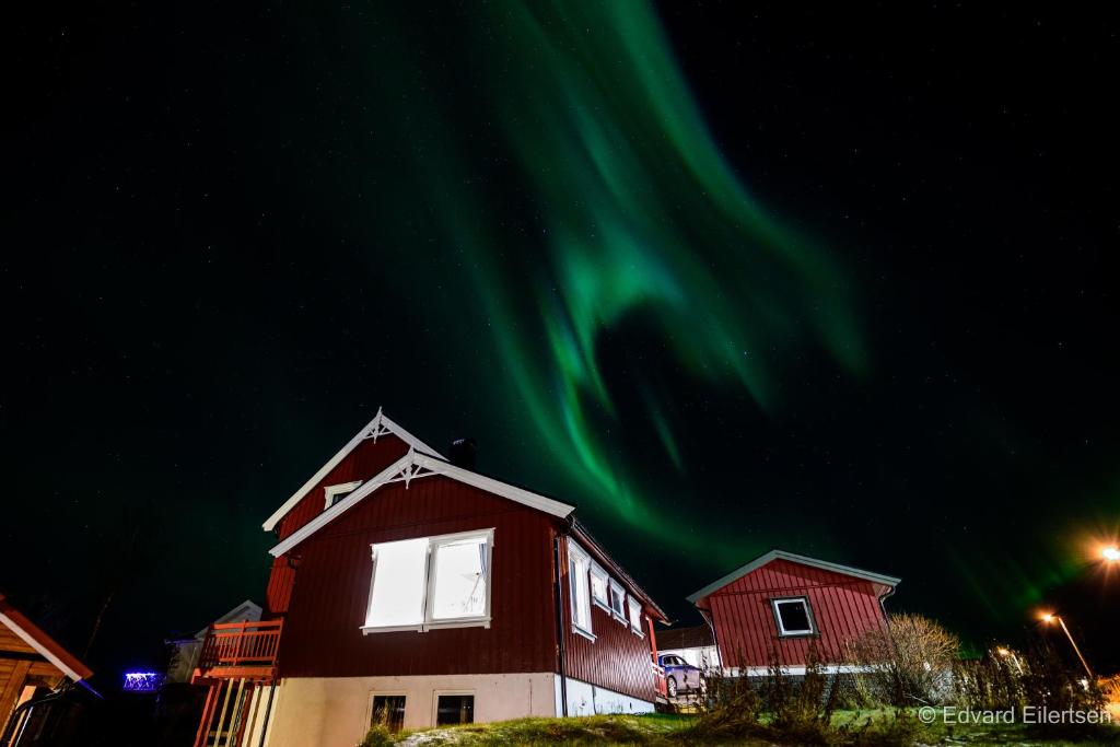ein Haus mit den grünen Nordlichtern am Himmel in der Unterkunft Cozy house on Sommarøy in Sommarøy