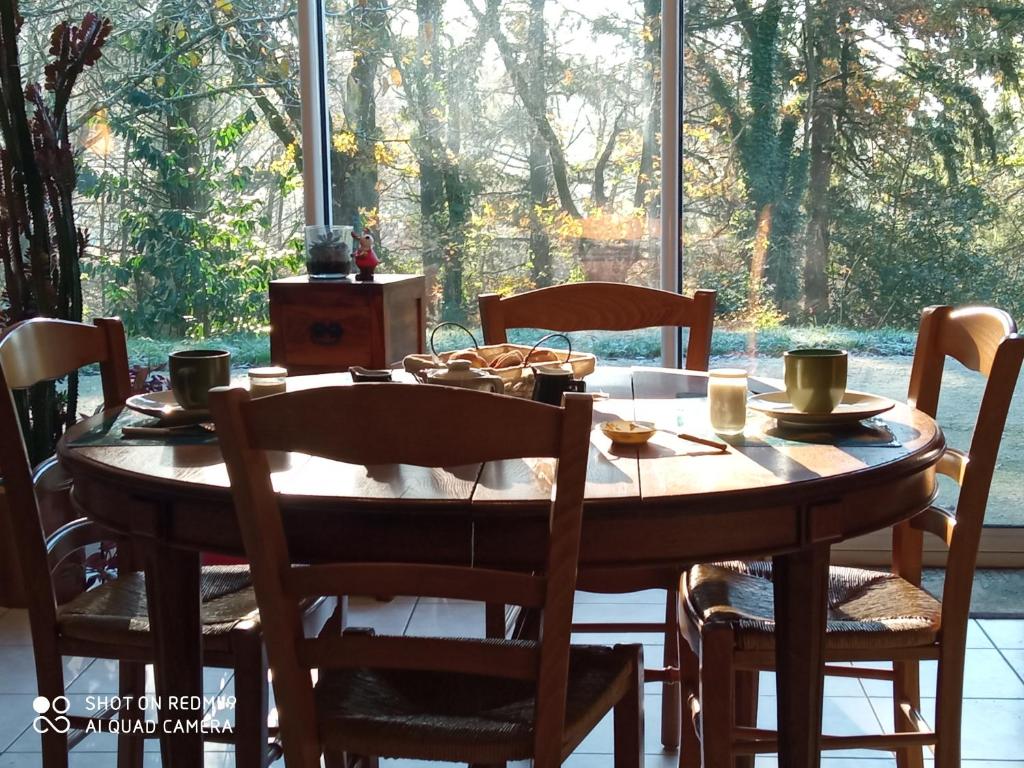 une table à manger avec des chaises et une grande fenêtre dans l'établissement Les Trois Geais, aux Épesses