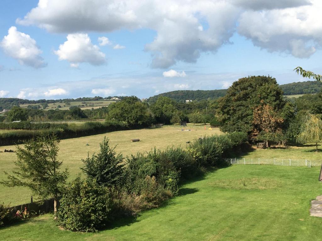 a green field with trees and animals in the distance at The Loft at Pen Orchard in Winscombe