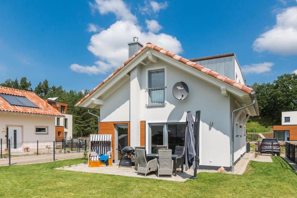 uma casa branca com mobiliário de pátio num quintal em 5 Sterne-Ferienhaus Eisvogel am See mit Sauna und Kamin em Krakow am See