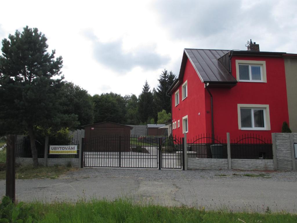een rood huis met een zwart dak naast een hek bij Chalupa Maršovice in Nové Město na Moravě