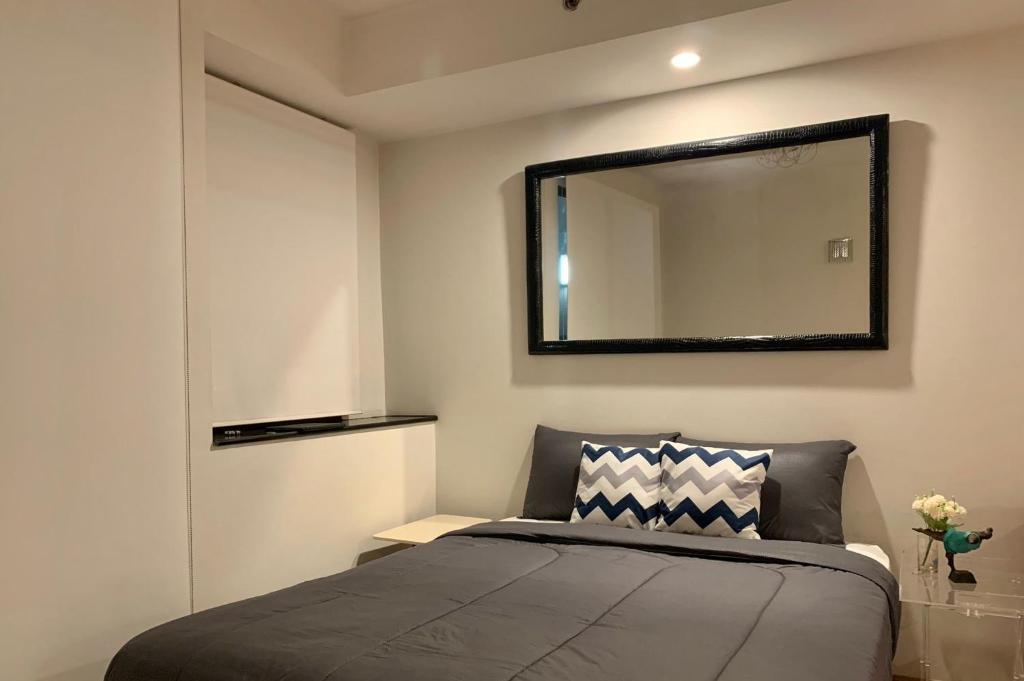 a bedroom with a bed and a mirror on the wall at Supalai Oriental Place in Bangkok