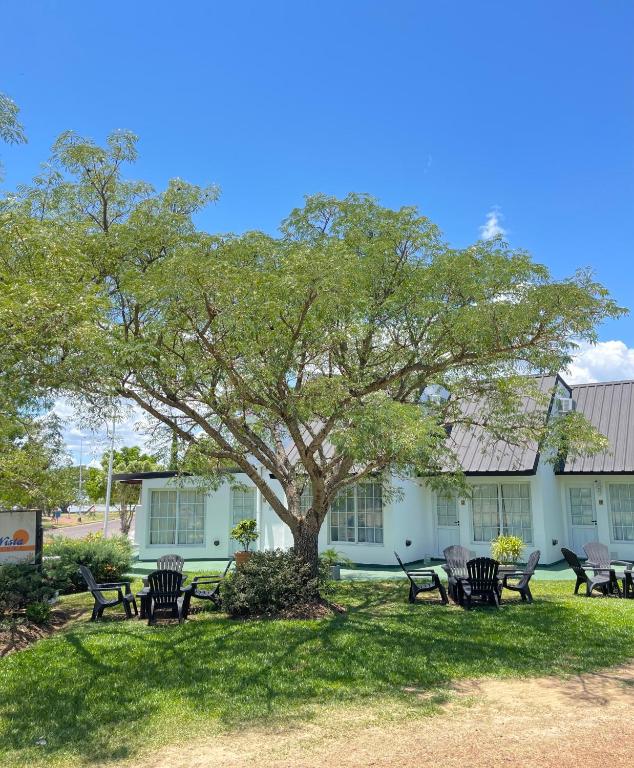 eine Gruppe von Stühlen unter einem Baum vor einem Gebäude in der Unterkunft Bungalows Bella Vista in Federación