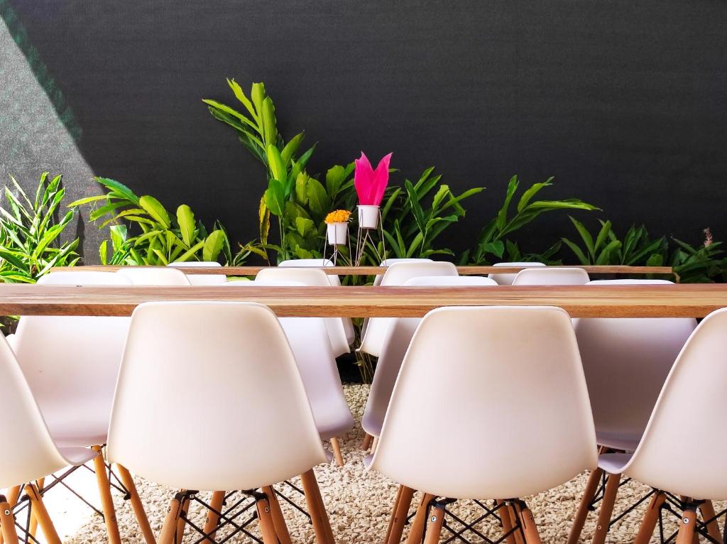 a conference table with white chairs and a pink flower at ICO Living Hostel in Santa Teresa Beach