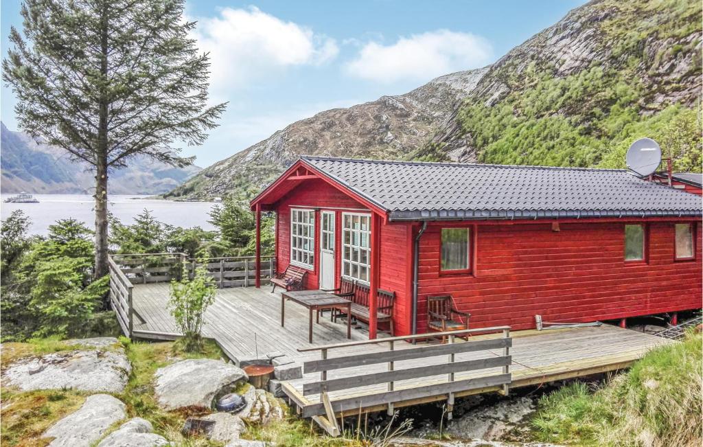 eine rote Hütte mit einer Holzterrasse neben einem See in der Unterkunft 3 Bedroom Lovely Home In Mly in Måløy