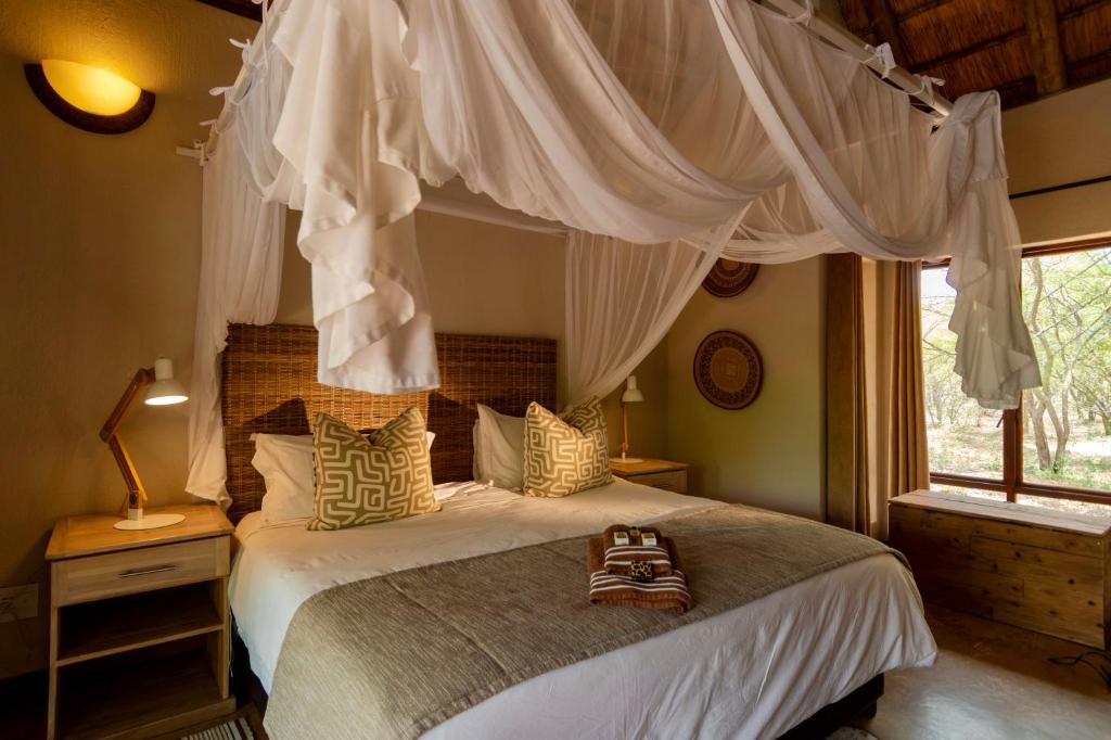 a bedroom with a canopy bed and a window at Giraffe Lodge in Hoedspruit