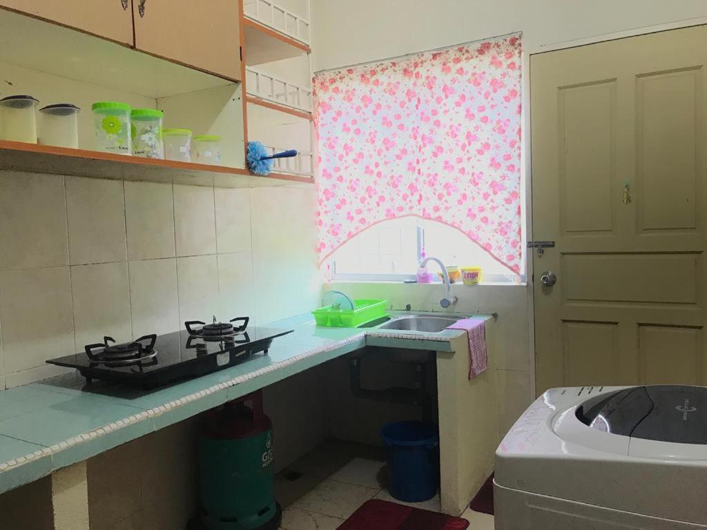 eine Küche mit einem Herd, einem Waschbecken und einem Fenster in der Unterkunft Homestay Din’s in Semporna