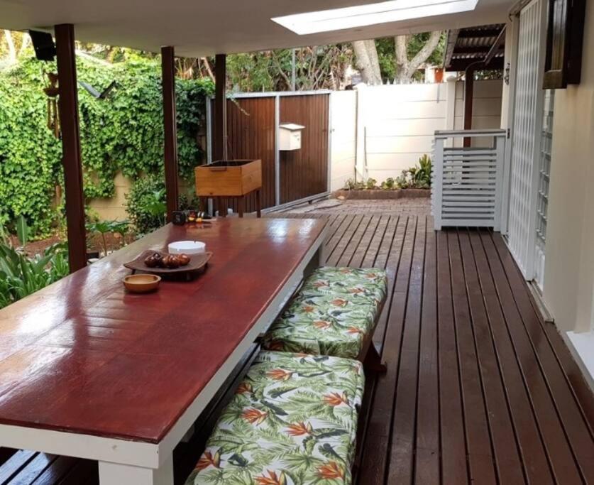 a wooden table with a bench on a deck at Tortuga - Peaceful Holiday Home with Loadshedding Backup in Sedgefield