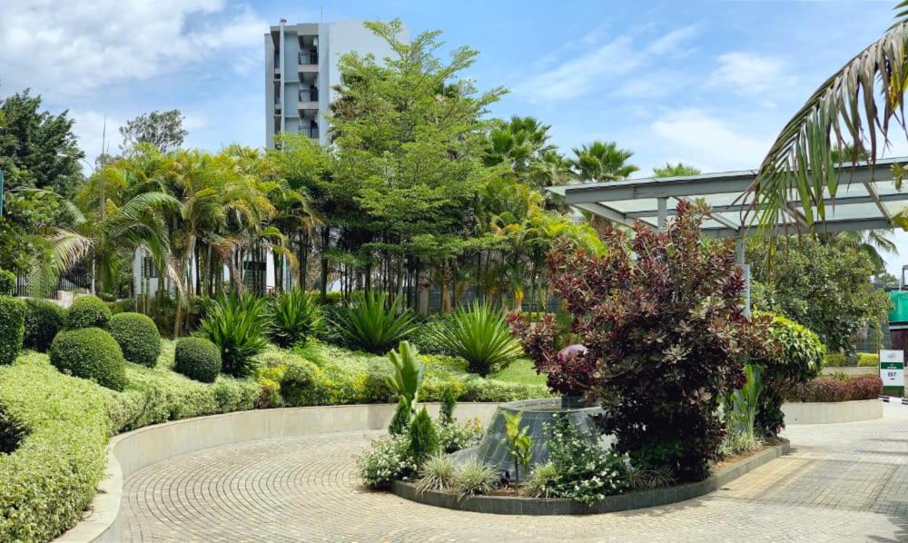 un giardino con molte piante e alberi e un edificio di Century Park Hotel & Residences a Kigali