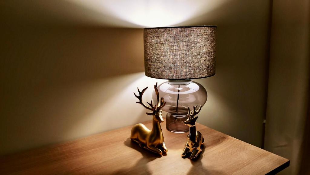 a lamp on a table with a deer figurine next to it at Mikołowski Sen in Mikołów