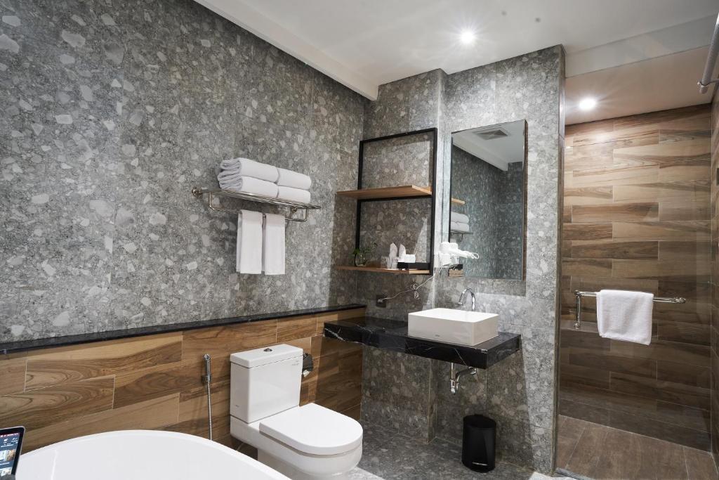een badkamer met een toilet, een wastafel en een spiegel bij Cordela Suites Tasikmalaya in Tasikmalaya