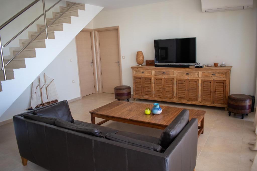 a living room with a couch and a table and a tv at Greek Villas Justine View Beach in Kyllini