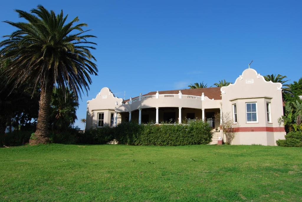 a white house with a palm tree in the yard at Anna's Farm Stay in Slangrivier