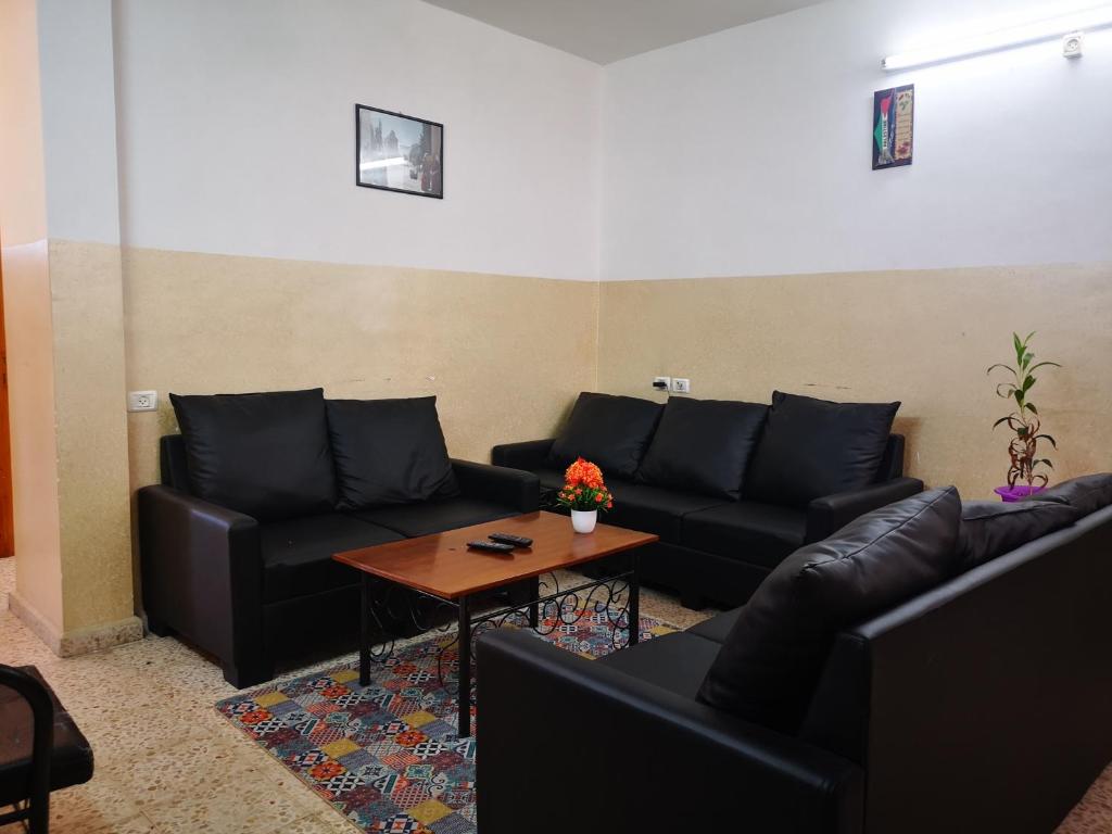 a living room with black leather couches and a table at YCC Guesthouse in Nablus