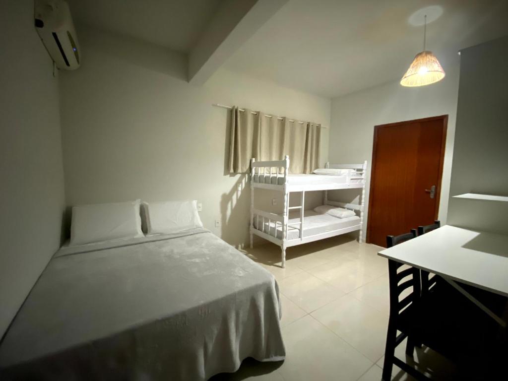 a bedroom with a bed and a table and a crib at Pousada Brunetti in Penha