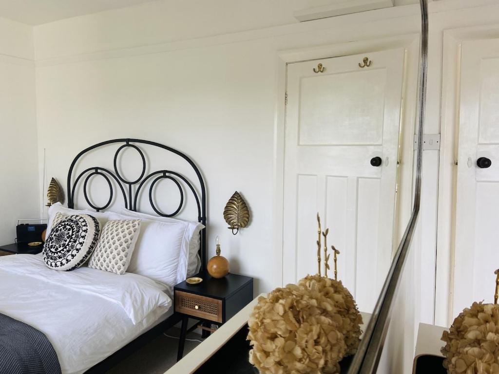 a bedroom with a white bed with a black headboard at Cottage Number 5 in Southwold - Charming cottage gardens in Southwold