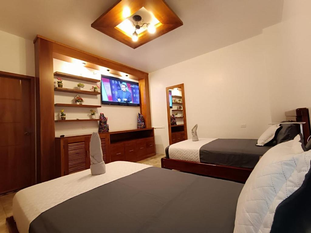 a bedroom with two beds and a flat screen tv at El Arco de Darwin in Puerto Ayora