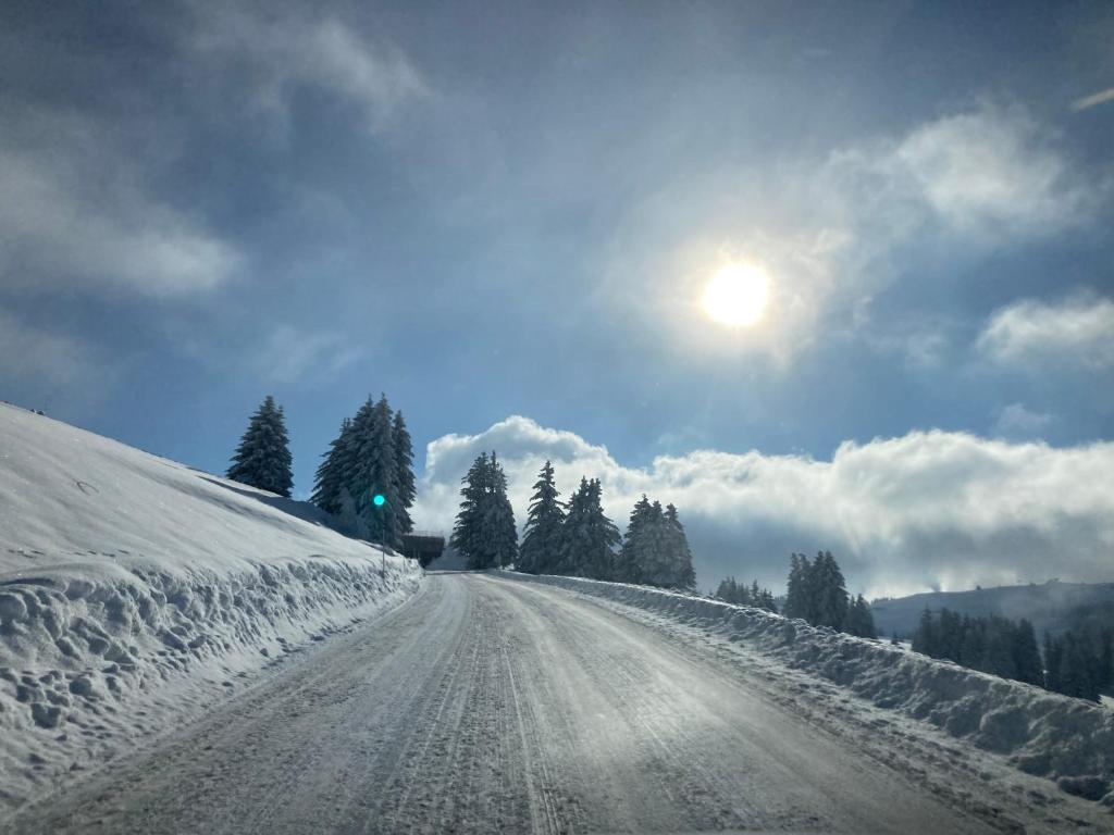 a road covered in snow with the sun in the sky at La forêt des Rennes in Villard-sur-Doron