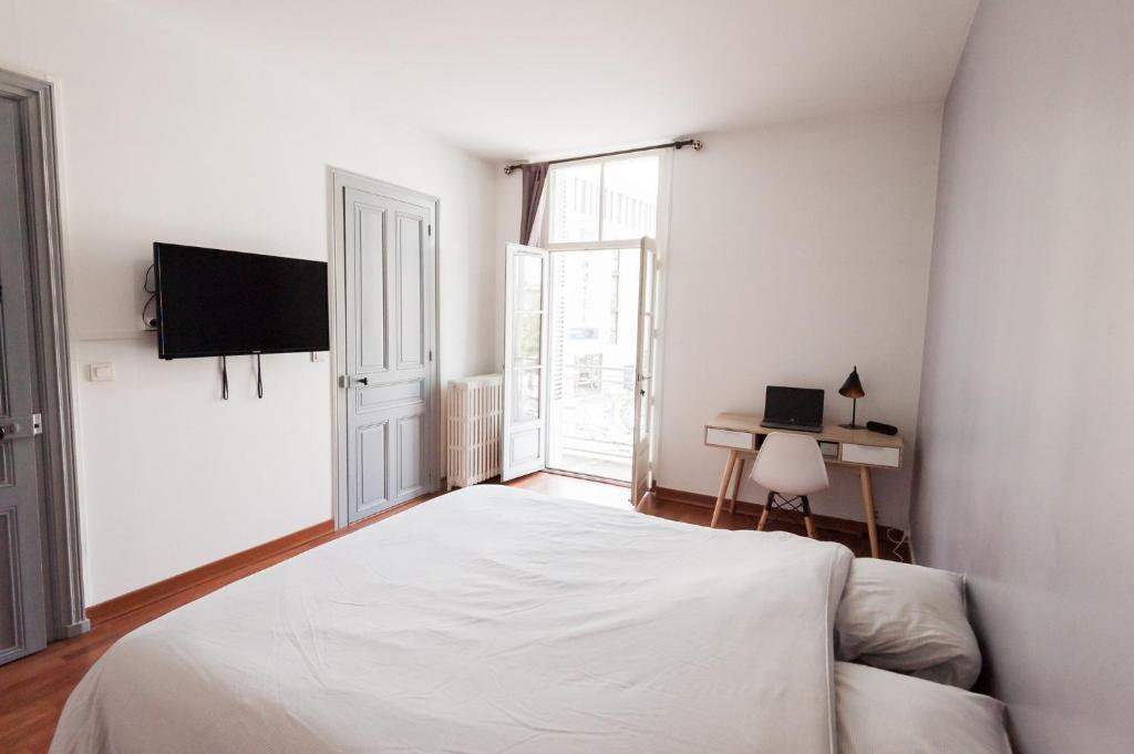 - une chambre blanche avec un lit et une télévision dans l'établissement Le Neptune Apt 85m2 3ch Appart Hotel Poitiers, à Poitiers