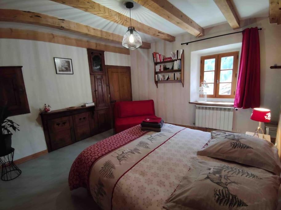 1 dormitorio con 1 cama grande y 1 silla roja en A l’Abri du Leschaux, en Le Petit-Bornand-lès-Glières