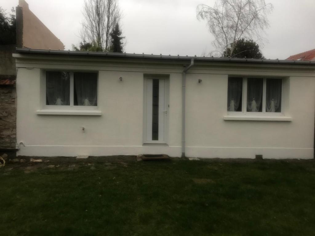 een wit huis met twee ramen en een tuin bij Maisonnette de charme au calme près des bords de Marnes in Saint-Maur-des-Fossés