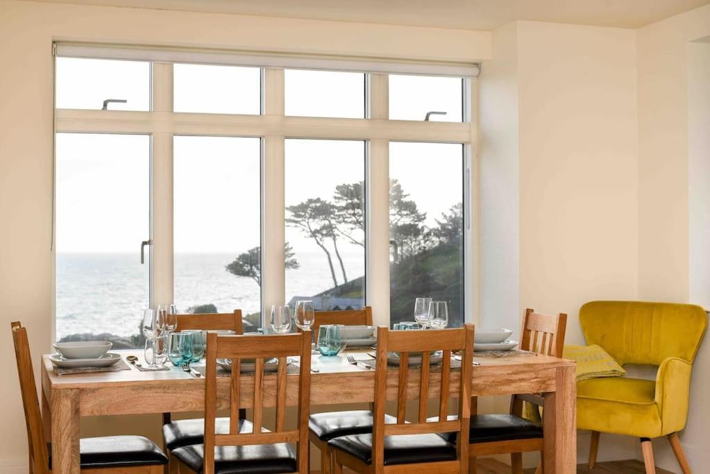 a dining room with a table and chairs with a view of the ocean at Fishermans Heights in Polperro
