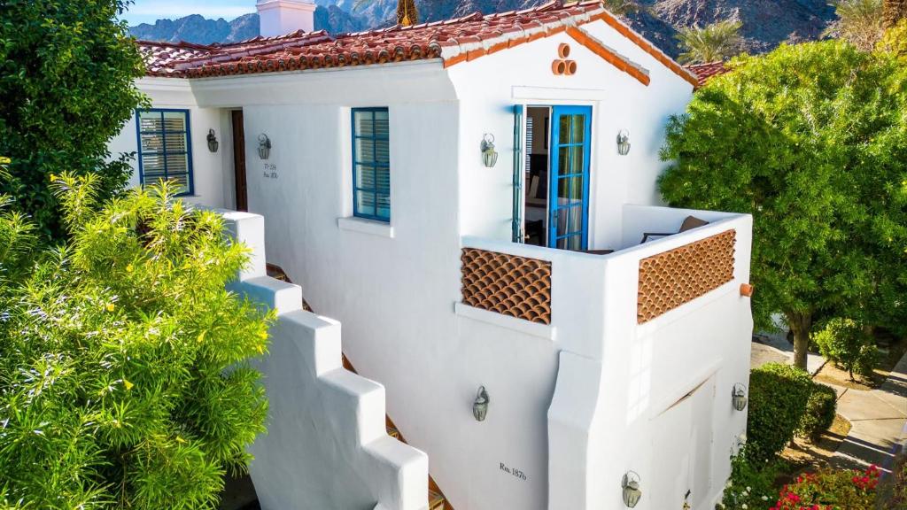 una casa blanca con una valla blanca y árboles en SV112 Spa Villa 1 Bedroom with Mountain Views, en La Quinta