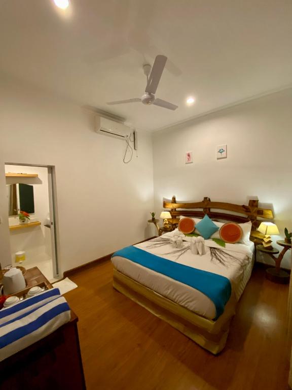 1 dormitorio con 1 cama grande y ventilador de techo en Holiday Rasdhoo Home, en Rasdu