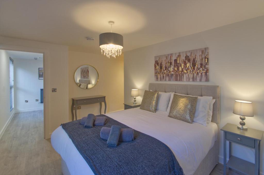 a bedroom with a large white bed with blue pillows at Marina Walk, New Luxury Coastal Apartment in The English Riviera, close to the Shops, Bars and Restaurants with Torquay Marina and Torre Abbey Sands Beach a short walk away! in Torquay