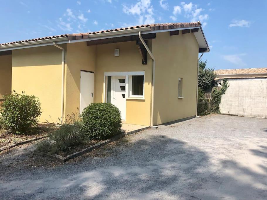 a small yellow house with a parking lot at Au calme, maison T3 neuf avec Jardin à Cassy in Lanton