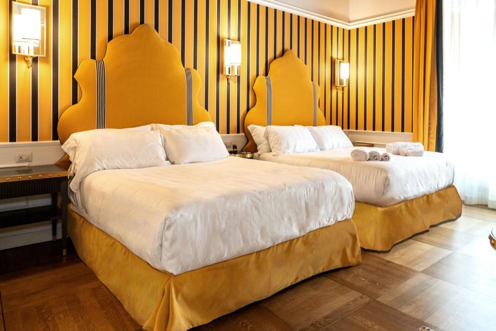 duas camas num quarto de hotel com paredes amarelas em Il Campo Marzio em Roma